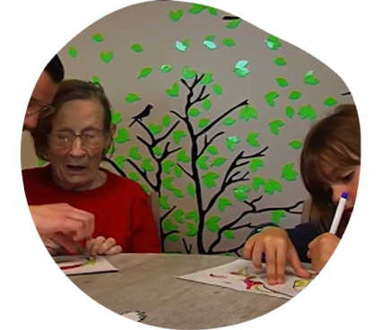 Une écolière et une résidente accompagnée d'un animateur de l'ehpad colorient un oiseau dans le cadre du programme "Drôle d'oiseaux" de la LPO.