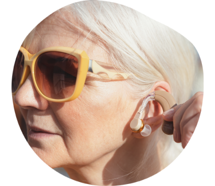 Une femme senior portant des lunettes de soleil s'équipe de prothèses auditives.